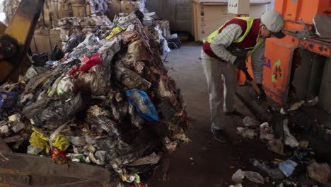 Two-workers-load-a-bale-of-non-recyclable-waste-onto-a-bulldozer-for-final-disposal