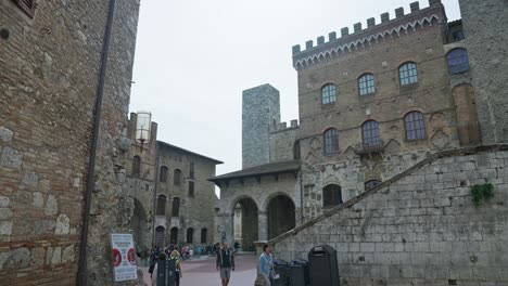 City-Square-Of-Piazza-del-Duomo-With-People-Travelling-On-A-Daytime-In-San-Gimignano,-Italy