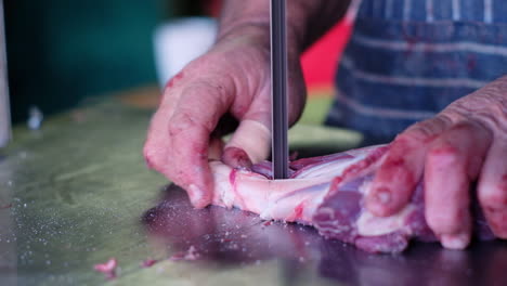 Butcher-cutting-up-leg-of-venison-into-stew-pieces-with-sharp-bandsaw,-close-up