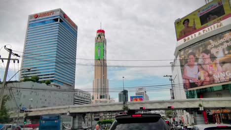 Baiyoke-Sky-Hotel-and-Other-Surrounding-Buildings-While-in-Traffic-in-Downtown-Bangkok,-Thailand