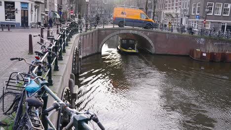 Boat-Tour-On-The-Canal-Passing-Under-The-Bridge-In-Amsterdam,-Netherlands