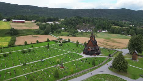 Heddal-Stave-Church-and-Headstones-in-Vestfold-og-Telemark,-Norway,-Scandinavia---Aerial-Circling