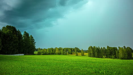 Timelapse-shot-of-dark-cloud-movement-over-green-grasslands-surrounded-by-tall-trees-on-a-cloudy-day