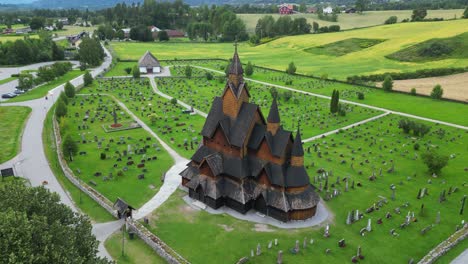 Heddal-Stave-Church-and-Headstones-in-Vestfold-og-Telemark,-Norway,-Scandinavia---Aerial-Backwards