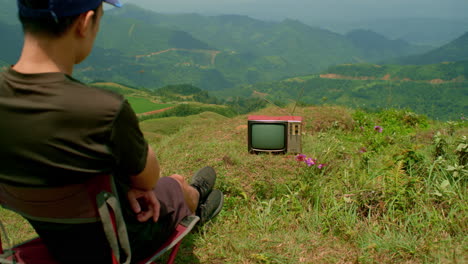 Amidst-nature's-beauty,-a-man-watches-an-old-TV-sparking-contemplation