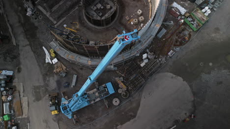 Top-shot-of-a-telescopic-construction-crane,-construction-site-in-the-background
