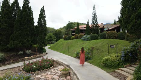 Lady-in-Red-Walking-Along-a-Botanical-Italian-Garden-Resort-in-Ratchaburi,-Thailand