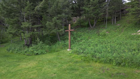Wooden-Christian-Cross-on-the-Edge-of-a-Forest-and-Open-Green-Grass-Field