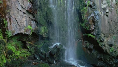 Nahaufnahme-Eines-Wasserfalls,-Der-Auf-Moosigen-Und-Felsigen-Klippen-Herabfließt