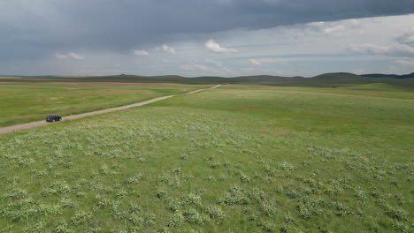 Montana-Green-Wild-Grass-Countryside-with-Dirt-Road-that-Car-is-Driving