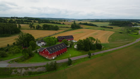 Aerial-over-country-road-and-red-barns-on-farm-in-Norwegian-countryside