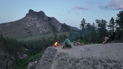 Friends-on-boulder-with-campfire,-epic-view-of-Sheeprock,-San-Isabel