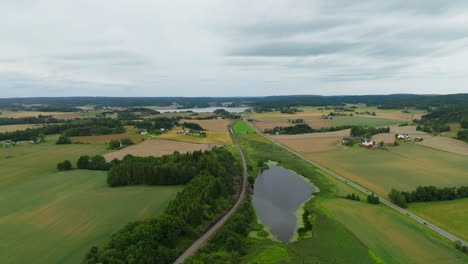 Highway-with-traffic-running-through-green-Norwegian-countryside,-aerial-riser