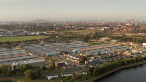 Circling-aerial-shot-over-large-water-treatment-plant-towards-central-London