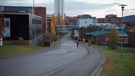 Gente-En-Bicicleta,-Trotando-Y-Caminando-Por-La-Calle-En-Una-Mañana-De-Otoño-En-El-Parque-Industrial-De-Tromso,-Noruega
