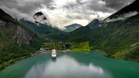 Aerial-hyperlapse-view-of-cruise-ship-docked-in-scenic-fjord,-Geiranger,-Norway