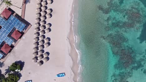 Aerial-top-down-shot-of-sunshades-at-sandy-beach-of-Quemaito-and-clear-sea-water-in-summer
