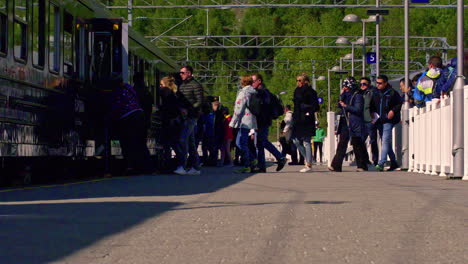 Slow-motion-shot-of-passengers-queuing-up-and-getting-on-a-train-at-a-railway-station-on-a-sunny-day