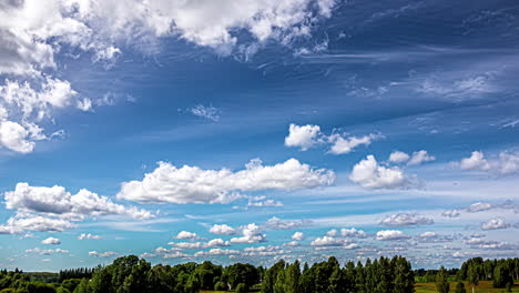 Flauschige-Wolken-Wehen-In-Eine-Richtung,-Während-Eine-Windscherung-Dünne-Zirruswolken-In-Eine-Andere-Richtung-über-Einem-Wald-Drückt-–-Zeitraffer