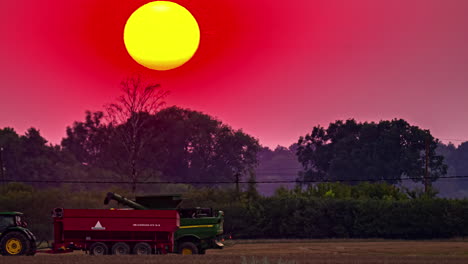 Timelapse-shot-of-combine-harvester-harvesting-along-ripe-wheat-field-with-sun-setting-in-the-background-during-evening-time
