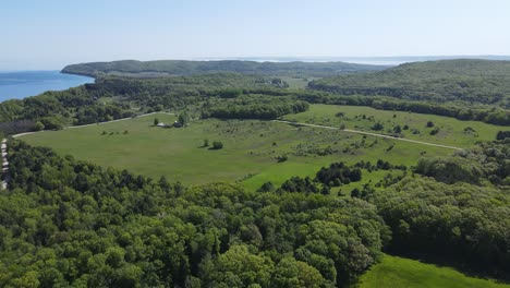 Farmland-and-woodland-near-shoreline-of-Michigan-lake,-aerial-view