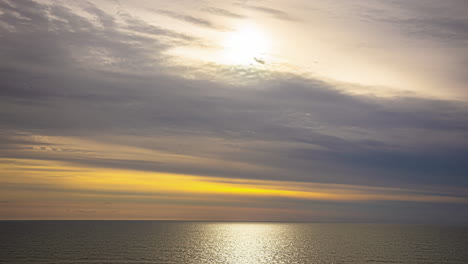 Timelapse-of-Late-Afternoon-Sunlight-Piercing-Through-Drifting-Clouds-over-the-Ocean-with-Yellow-Skies