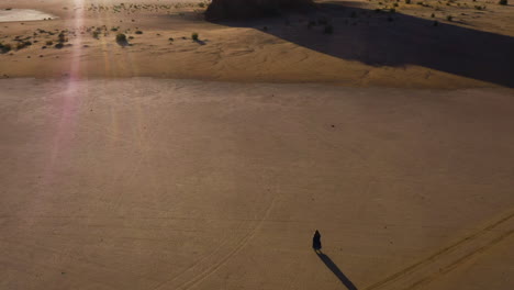 Luftaufnahme-Nach-Hinten-über-Einer-Person,-Die-In-Der-Sonnenbeschienenen-Wüste-In-Saudi-Arabien-Läuft