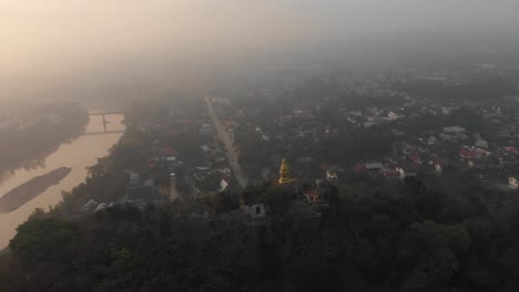 Orbit-around-famous-Phousi-hill-at-luang-prabang-during-sunrise,-aerial