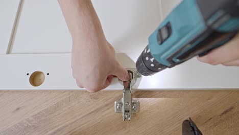 POV-using-electric-drill-to-secure-screw-along-self-assemble-closet-door,-top-down