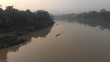 Kleines-Lokales-Boot-Fährt-Bei-Sonnenaufgang-Auf-Dem-Fluss-In-Laos,-Luftaufnahmen
