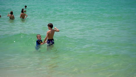 Fröhliches-Kind,-Das-An-Einem-Sommertag-Im-Wasser-Des-Meeres-Spielt-Und-Dabei-Eine-Farbenfrohe-Schwimmring-Schwimmweste-Trägt
