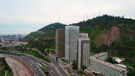 Flying-towards-Santa-María-Towers-by-mapocho-River-and-San-Cristobal-Hill-Background,-Chile