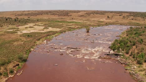 Aerial-drone-shot-of-Africa-Landscape-of-Masai-Mara-Beautiful-River-Landscape-Scenery-in-Maasai-Mara-National-Reserve-in-Kenya,-Africa,-Establishing-Shot-Following-Flowing-Water