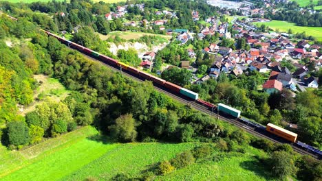 Luftdrohne-über-Einem-Güterzug,-Der-An-Einem-Ländlichen-Dorf-Vorbeifährt-4k