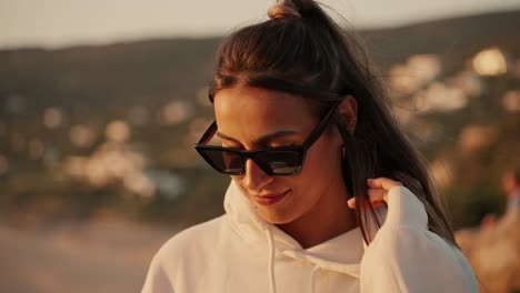 Slow-Motion-Shot-Of-Girl-Moving-Fingers-Into-Her-Beautiful-Brown-Hair-with-sunglasses-at-sunset