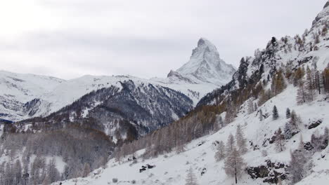 Opening-scenic-cinematic-aerial-drone-Zermatt-Switzerlands-most-famous-snow-cover-mountain-Matterhorn-October-November-heavy-fresh-snowfall-already-winter-on-climbing-peak-yellow-autumn-trees-down-jib
