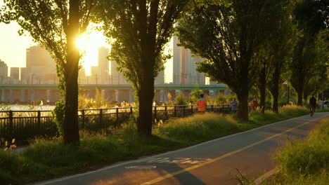 Gente-En-El-Parque-Yongsan-Hangang-Con-Un-Puente-Ferroviario-Sobre-El-Río-Han-Durante-El-Amanecer-En-Seúl,-Corea-Del-Sur