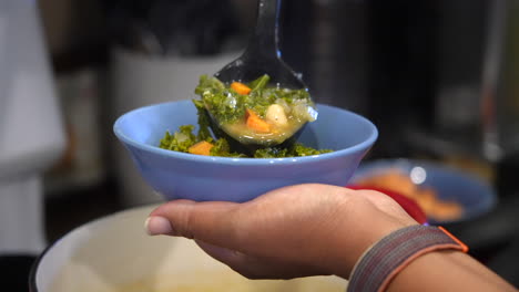 Plating-a-bowl-of-kale-and-white-bean-soup---slow-motion