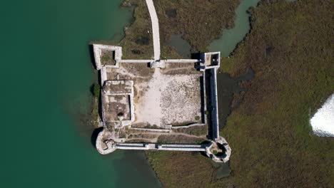 Extraordinary-Medieval-Castle,-Historic-Gem-Surrounded-by-Turquoise-Waters-on-the-Shallow-Lagoon-of-Butrint,-Top-Down-View
