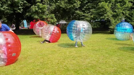 Kinder-In-Riesigen-Blasenfußballbällen-Kämpfen-Darum,-Aufblasbare-Spiele-Im-Freien-Aufzustellen