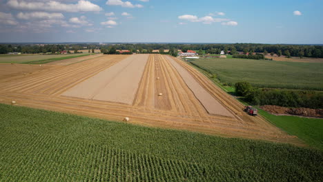 Aerial-rural-atmosphere,-mowed-field-with-tractor,-straw-baling,-wide-shot-of-cultivated-fields,-harvest-season-in-Poland