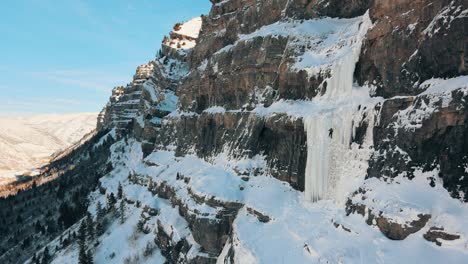 Drone-shot-of-professional-mountain-climber-climbing-on-ice-and-snowy-mountain-wall