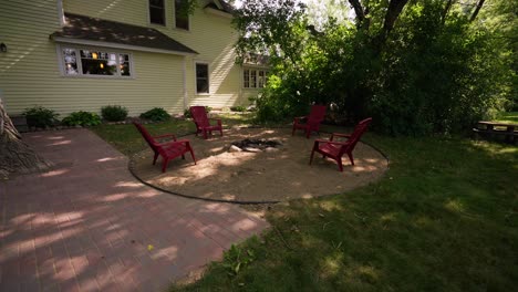 wide-pull-back-of-a-fire-pit-surrounded-by-sand-and-red-Adirondack-chairs