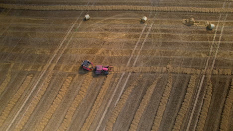 Top-down-aerial---a-tractor-with-a-specialized-machine-creates-straw-bales---technology-in-agriculture---improving-fieldwork-efficiency