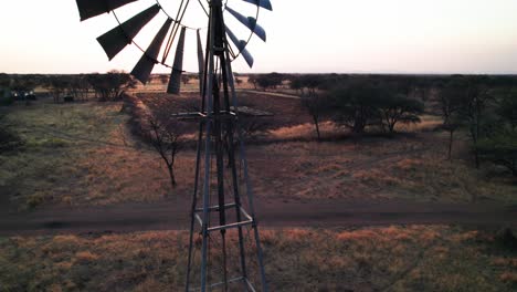 Windpumpe-Im-Afrikanischen-Busch-Mit-Sonnenuntergang,-Der-Durch-Flügel-Kriecht