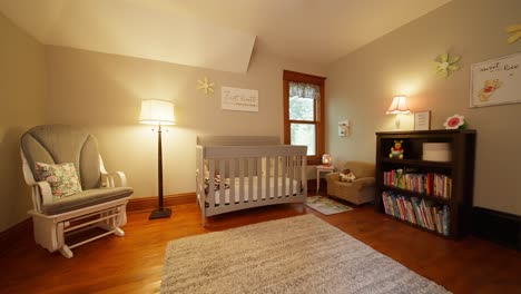 wide-push-in-of-a-nursery-with-a-grey-baby-crib,-rocking-chair,-book-shelf,-and-a-lamp