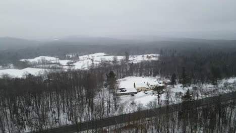 Winter-in-Vermont:-Snowy-landscapes,-leafless-trees,-tranquil-road,-and-cozy-home-under-cloudy-skies