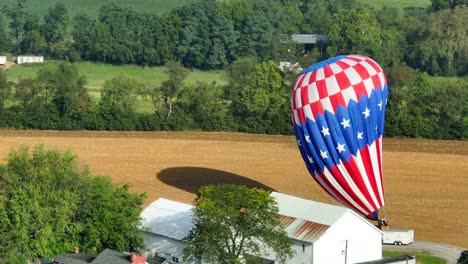 Hot-air-balloon-with-an-American-flag-deflating-after-landing-in-rural-field-in-United-States