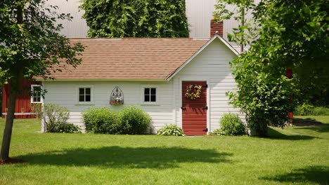 static-shot-of-a-white-building-with-a-red-door-on-a-farm-on-a-sunny-day