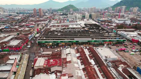 Aerial-view-establishing-the-Vega-Central,-Santiago-Chile's-main-grocery-market,-surrounding-impoverished-houses-with-zinc-roofs